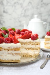 Photo of Tasty sponge cake with fresh berries and mint on light gray table, closeup