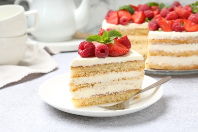 Photo of Tasty sponge cake with fresh berries and mint served on light gray table, closeup