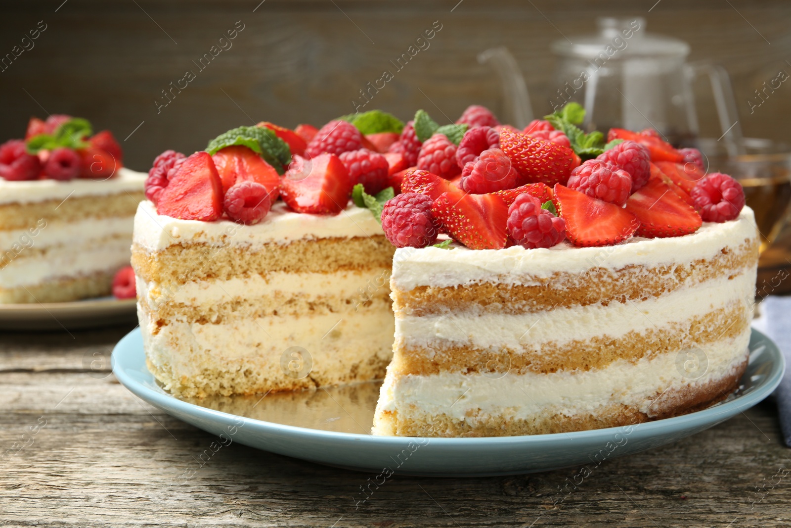 Photo of Tasty sponge cake with fresh berries and mint on wooden table, closeup