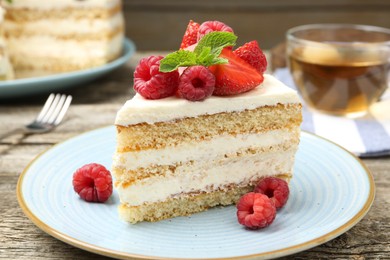 Photo of Piece of tasty sponge cake with fresh berries and mint on wooden table, closeup