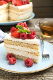 Photo of Piece of tasty sponge cake with fresh berries and mint served on wooden table, closeup