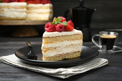 Photo of Piece of tasty sponge cake with fresh berries and mint served on black wooden table