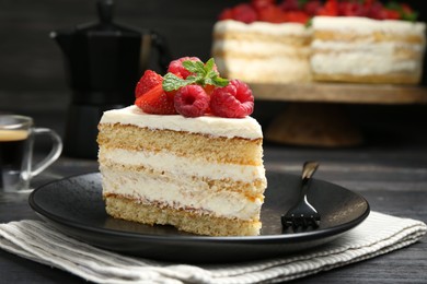 Photo of Piece of tasty sponge cake with fresh berries and mint served on black wooden table, closeup