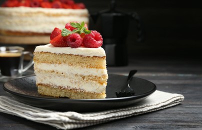 Piece of tasty sponge cake with fresh berries and mint served on black wooden table, closeup