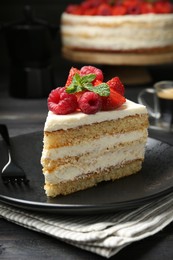 Photo of Piece of tasty sponge cake with fresh berries and mint served on black wooden table, closeup