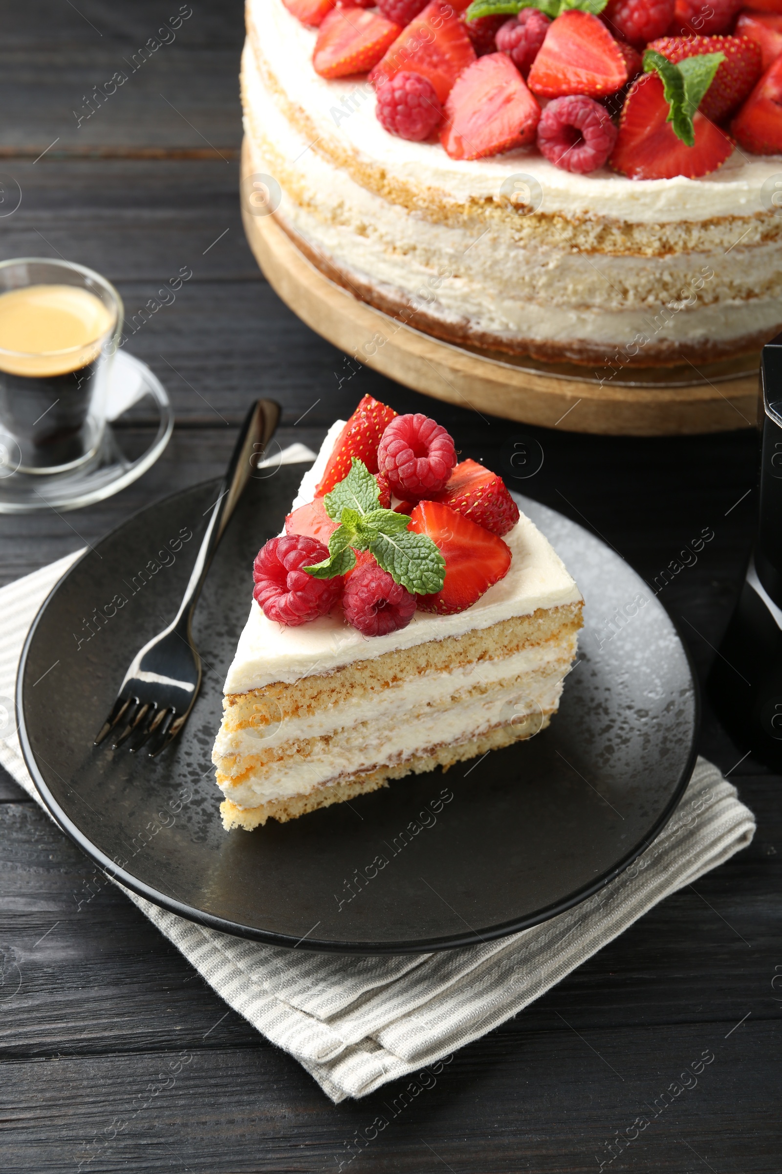 Photo of Tasty sponge cake with fresh berries and mint served on black wooden table