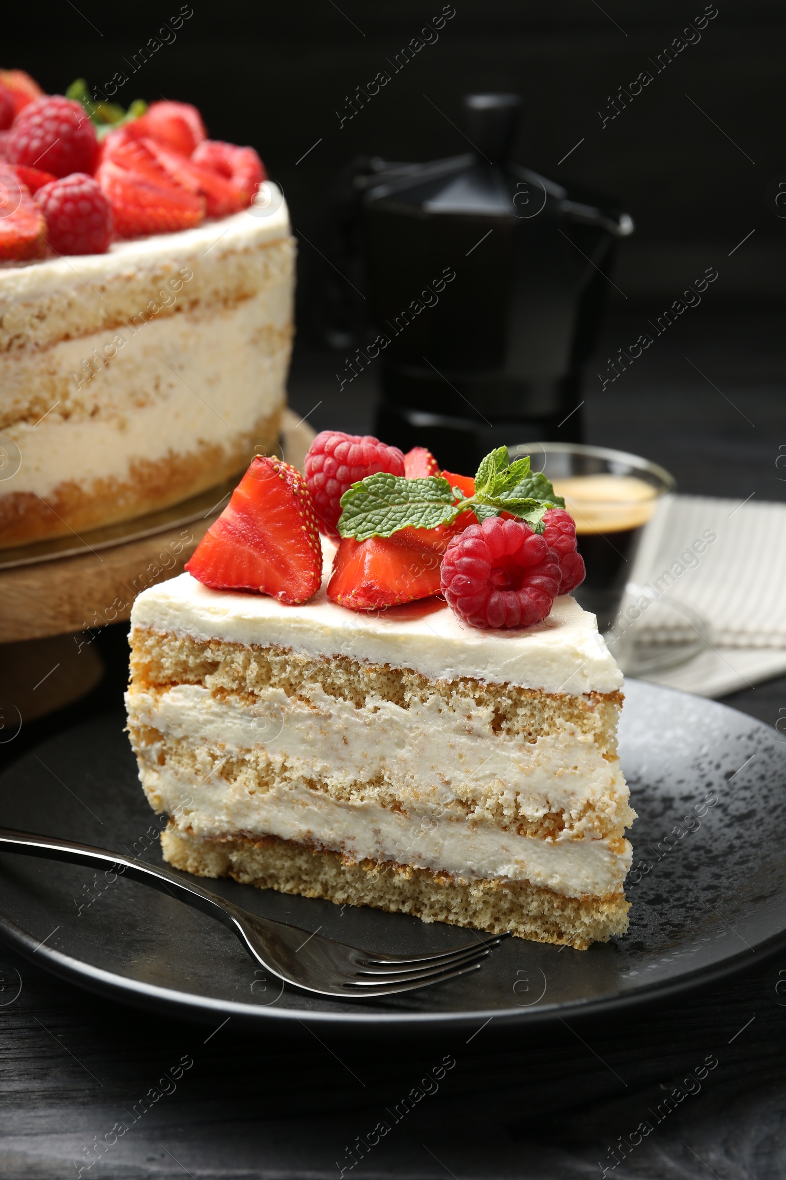 Photo of Tasty sponge cake with fresh berries and mint served on black table, closeup