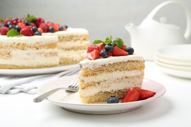 Photo of Tasty sponge cake with fresh berries and mint served on white table