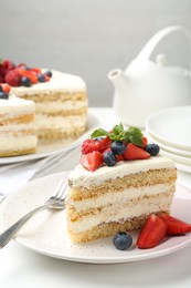 Tasty sponge cake with fresh berries and mint served on white table