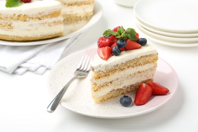 Photo of Tasty sponge cake with fresh berries and mint served on white table, closeup