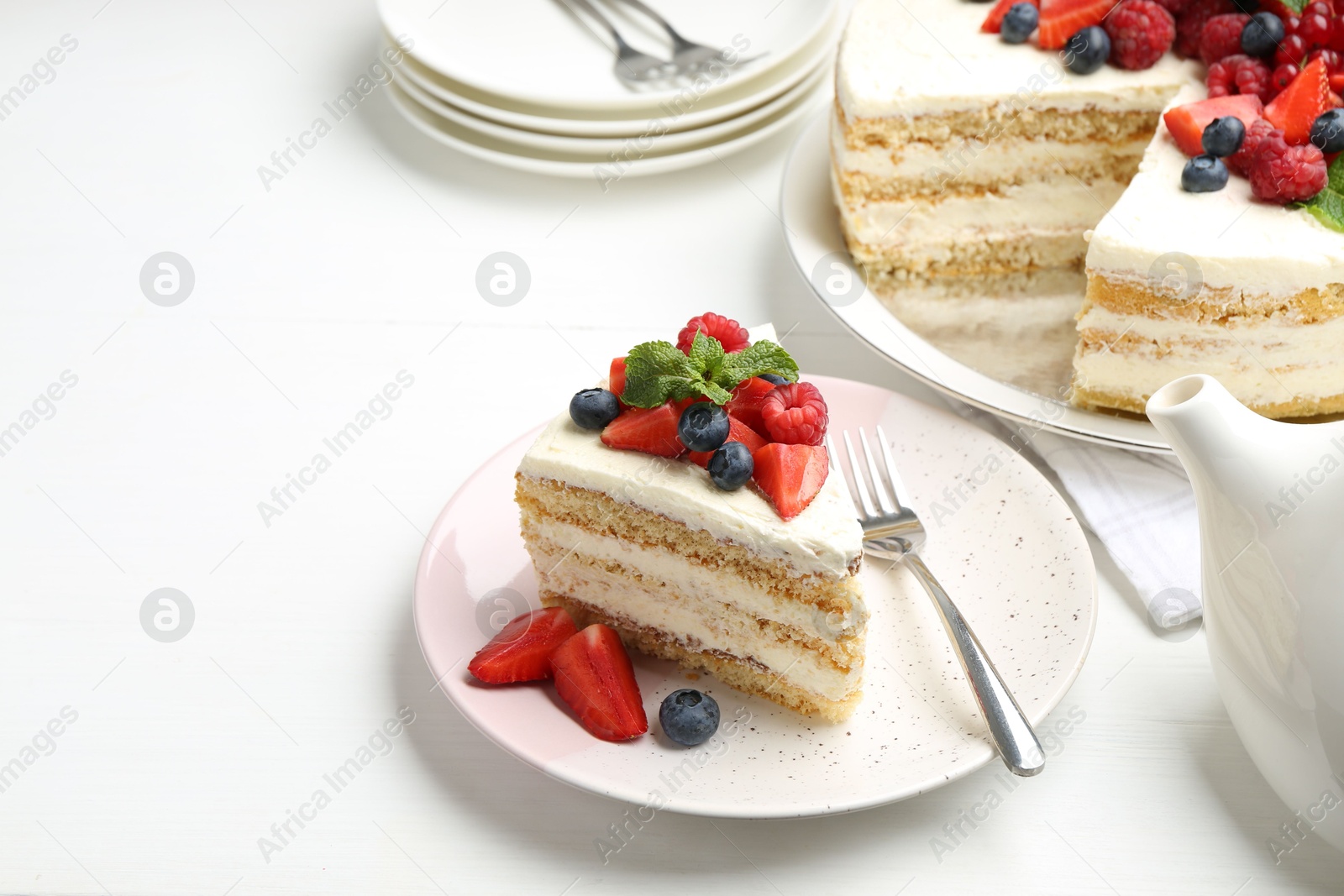 Photo of Tasty sponge cake with fresh berries and mint served on white table, space for text