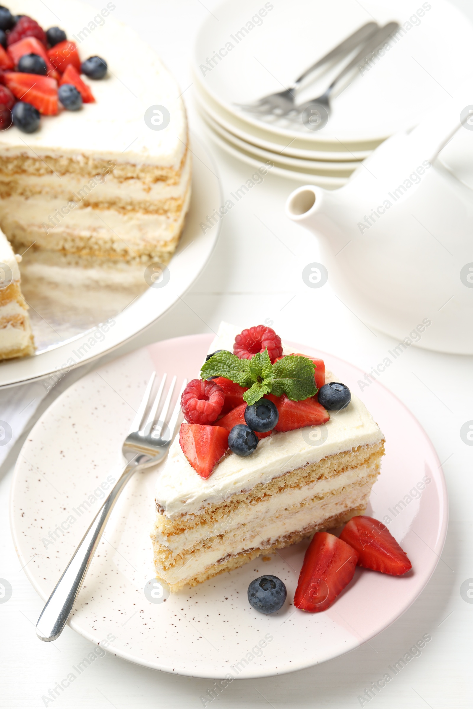 Photo of Tasty sponge cake with fresh berries and mint served on white table