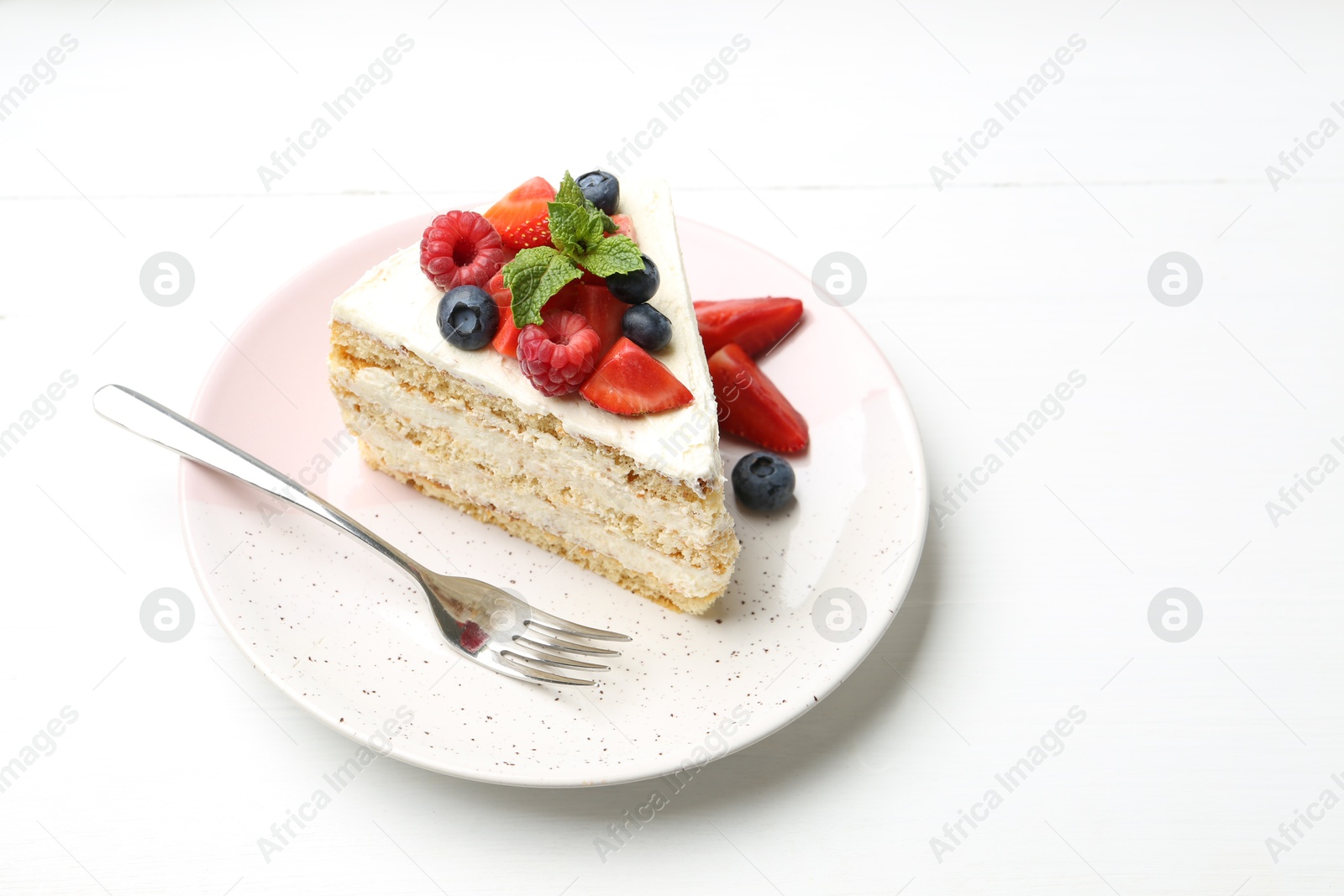 Photo of Tasty sponge cake with fresh berries and mint served on white table. Space for text