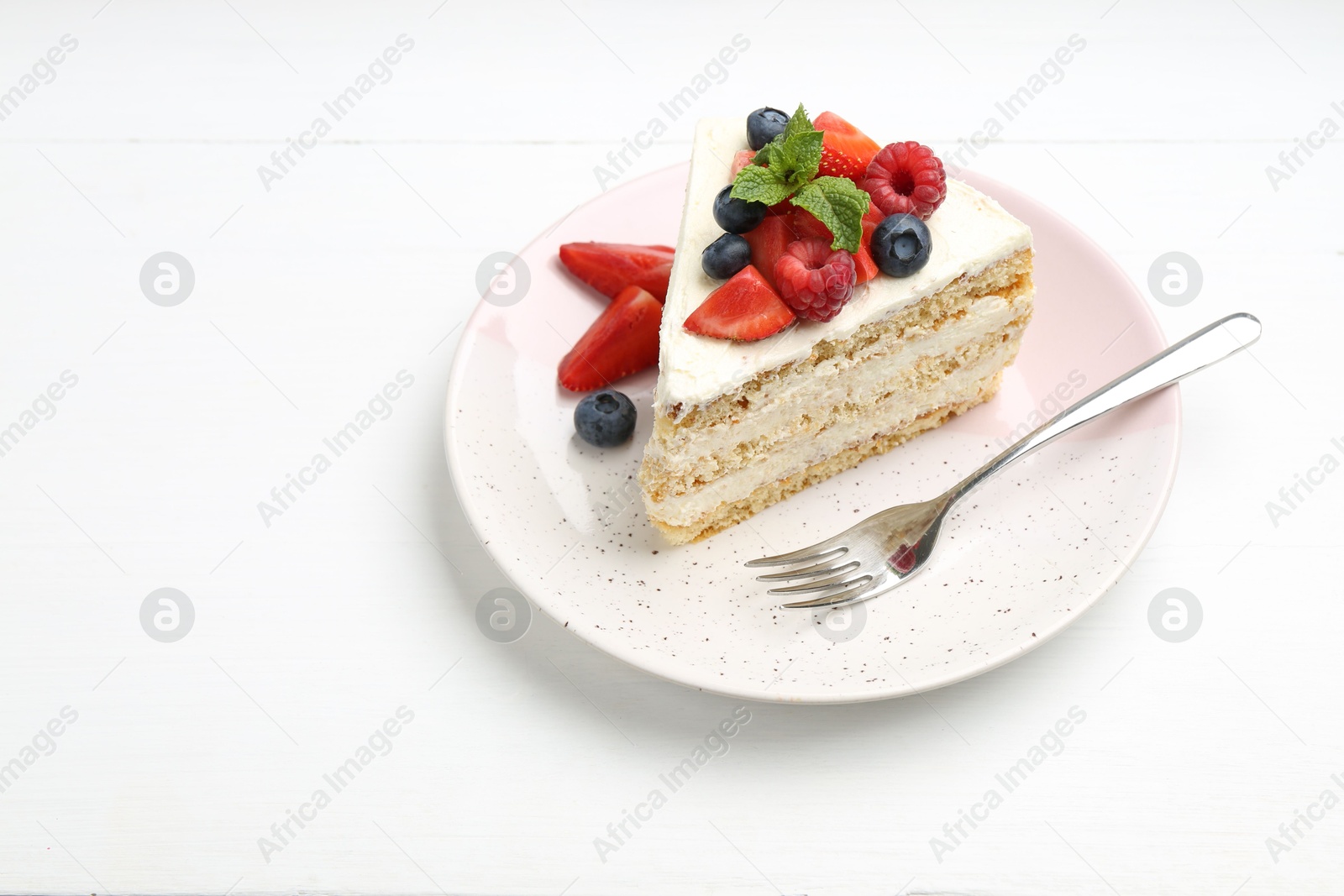 Photo of Tasty sponge cake with fresh berries and mint served on white table, space for text