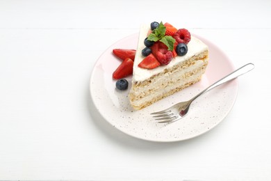 Photo of Tasty sponge cake with fresh berries and mint served on white table, space for text