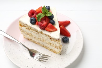 Tasty sponge cake with fresh berries and mint served on white table, closeup