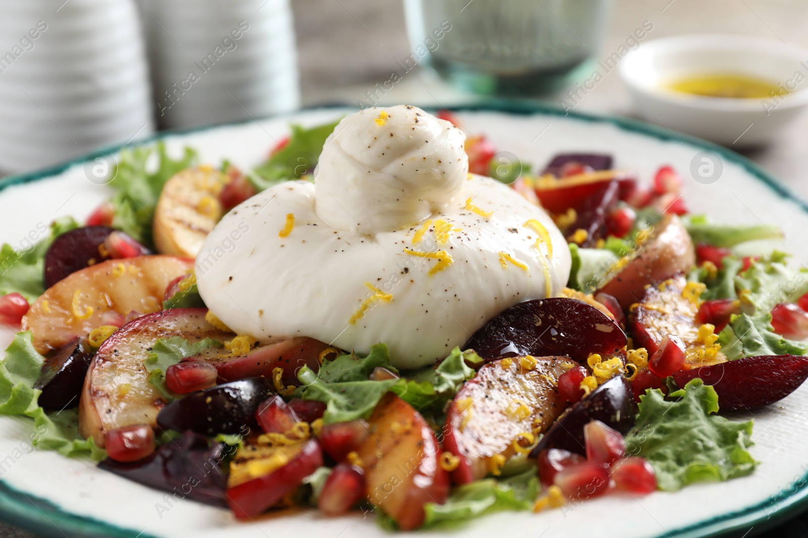 Photo of Plate with fresh burrata salad on table, closeup