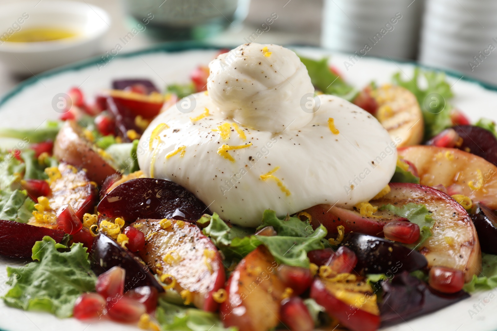 Photo of Plate with fresh burrata salad on table, closeup