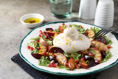 Photo of Plate with fresh burrata salad on grey textured table, closeup