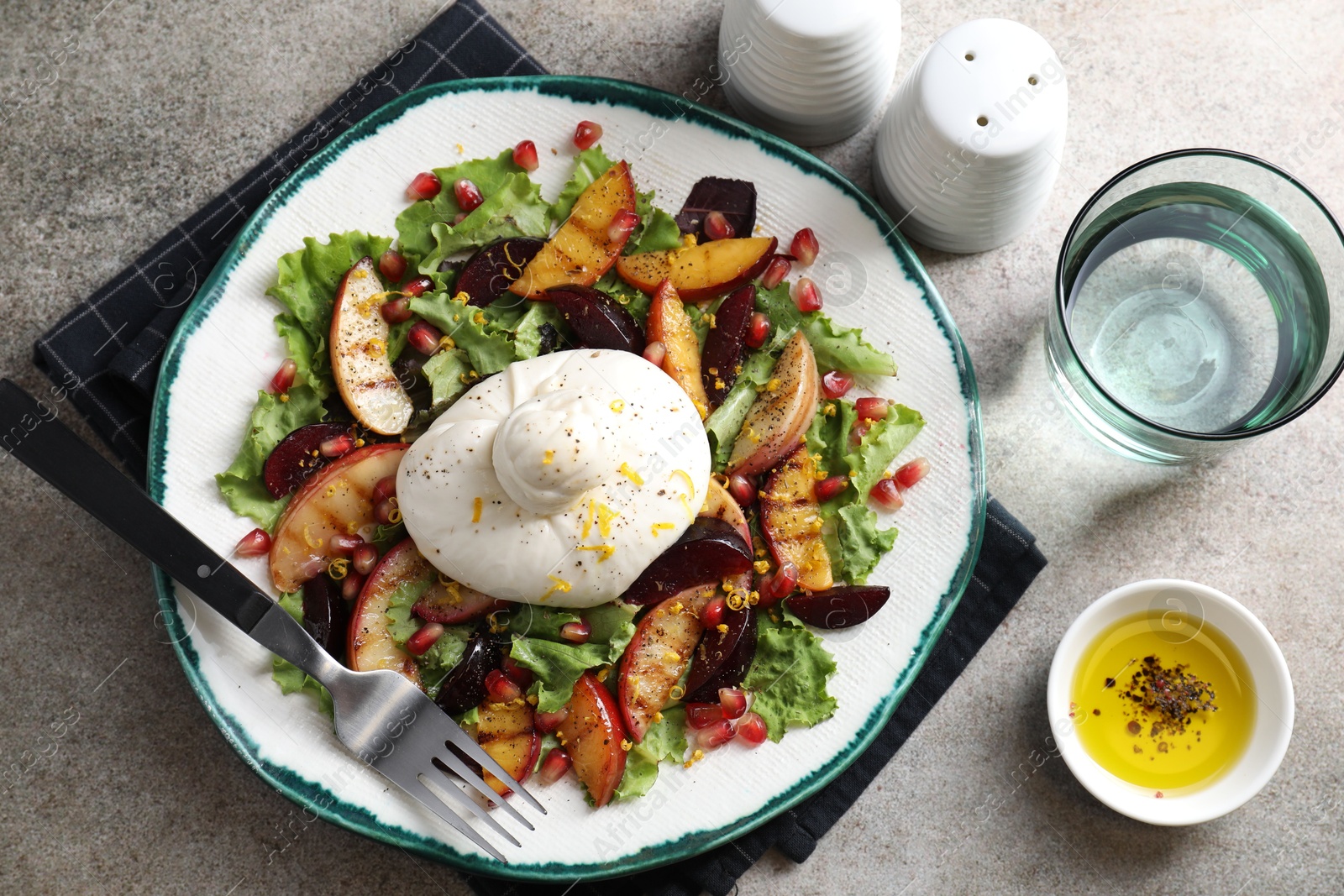 Photo of Plate with fresh burrata salad served on grey textured table, flat lay