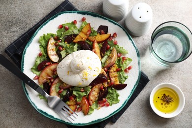 Plate with fresh burrata salad served on grey textured table, flat lay