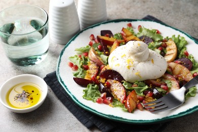 Photo of Plate with fresh burrata salad, oil and water on grey textured table, closeup