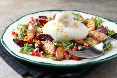 Plate with fresh burrata salad on grey textured table, closeup