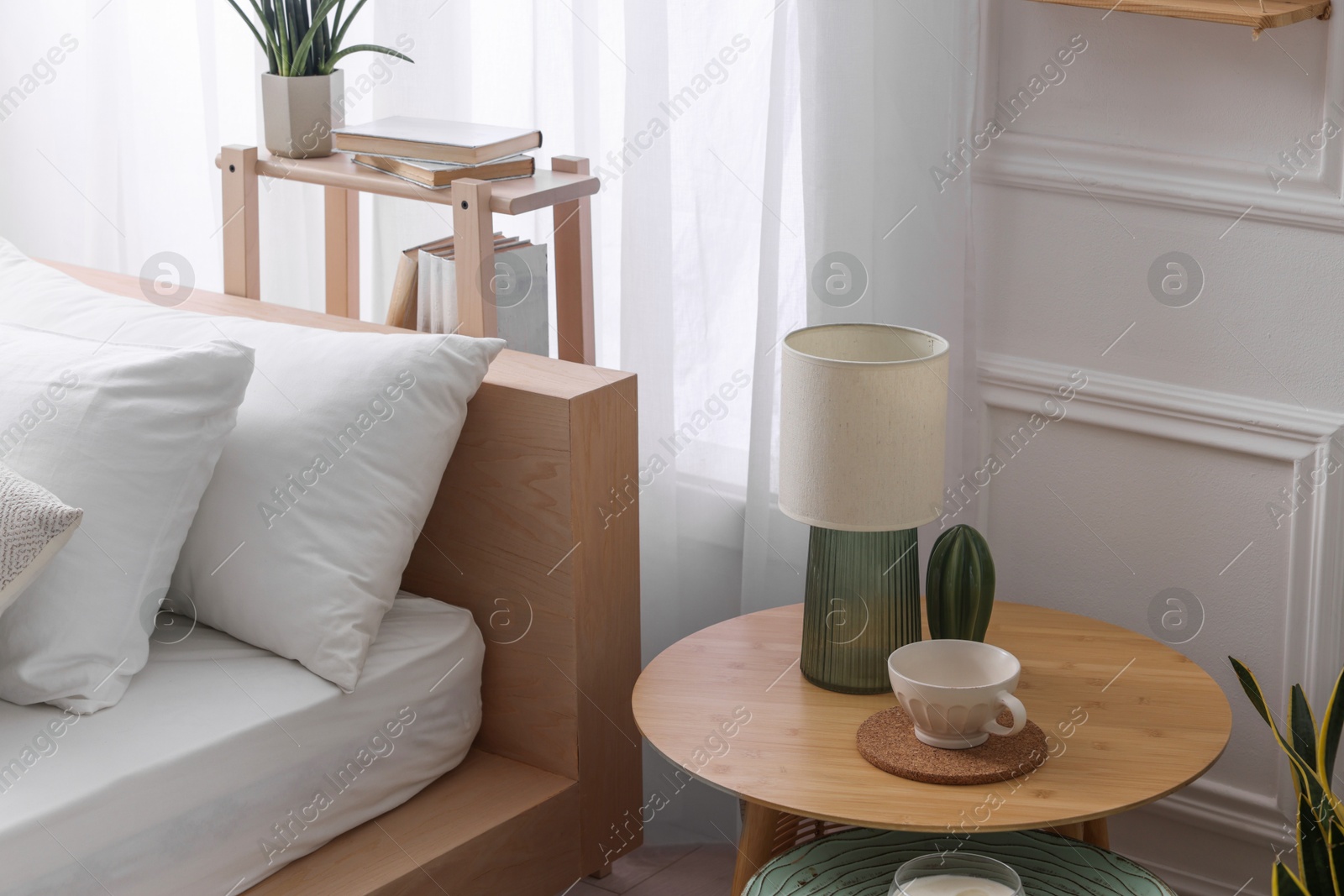 Photo of Stylish living room interior with bed, bedside tables, lamp and houseplants