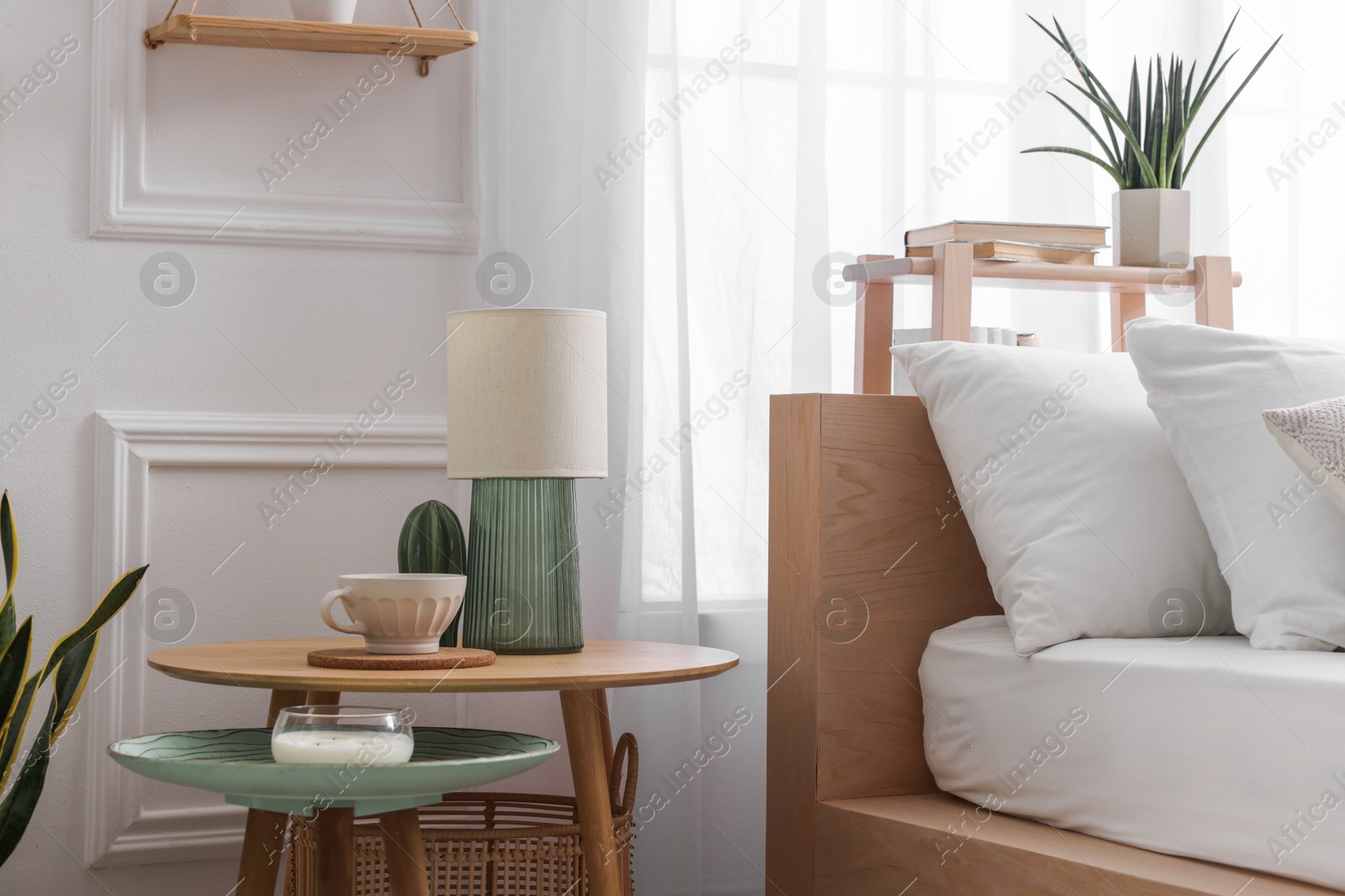 Photo of Stylish living room interior with bed, bedside tables, lamp and houseplants