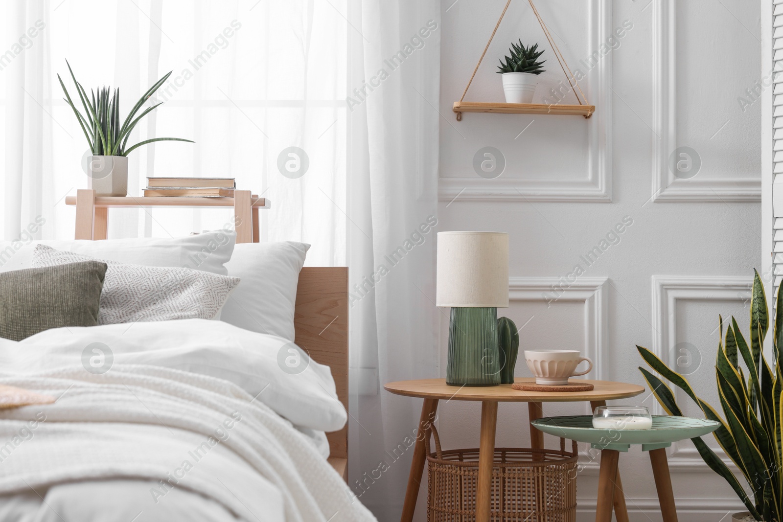 Photo of Stylish living room interior with bed, bedside tables, lamp and houseplants