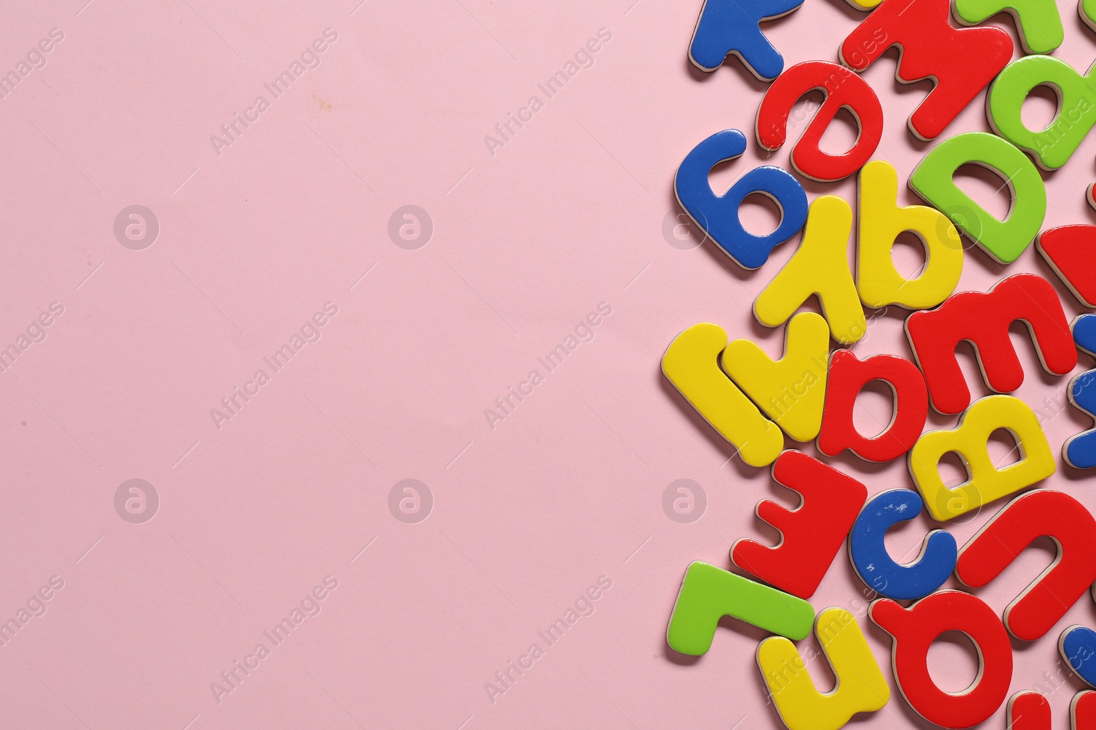 Photo of Learning alphabet. Magnetic letters on pink background, flat lay. Space for text