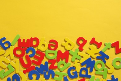 Learning alphabet. Magnetic letters on yellow background, flat lay. Space for text