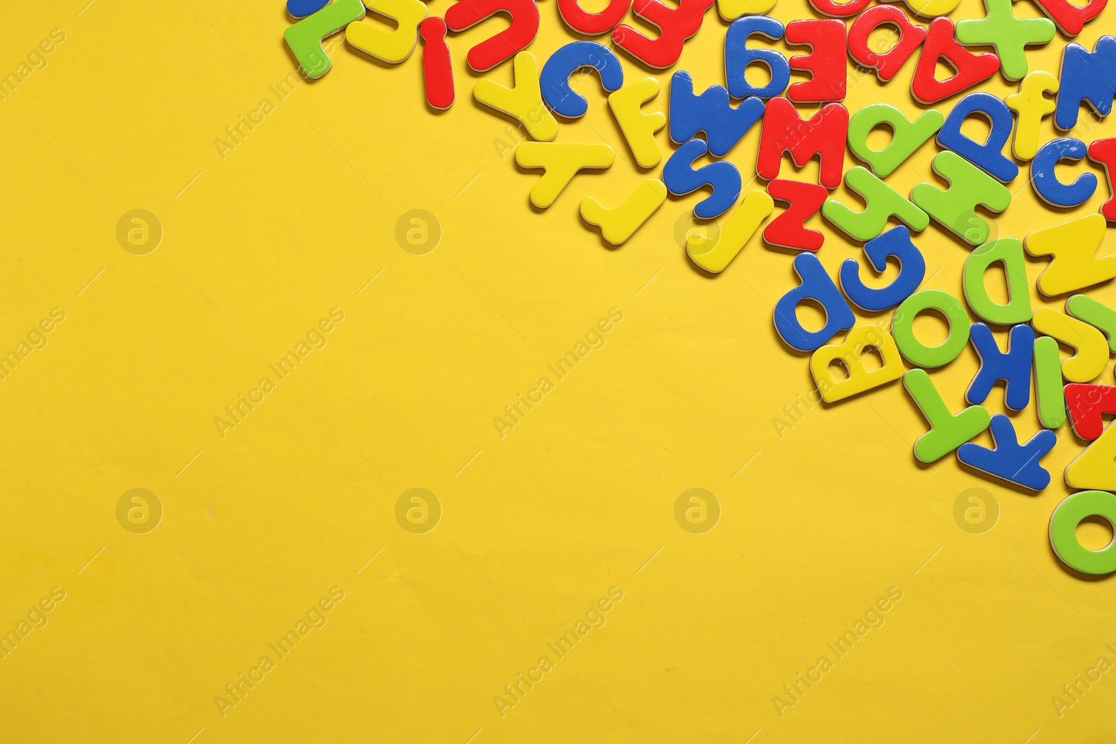 Photo of Learning alphabet. Magnetic letters on yellow background, flat lay. Space for text