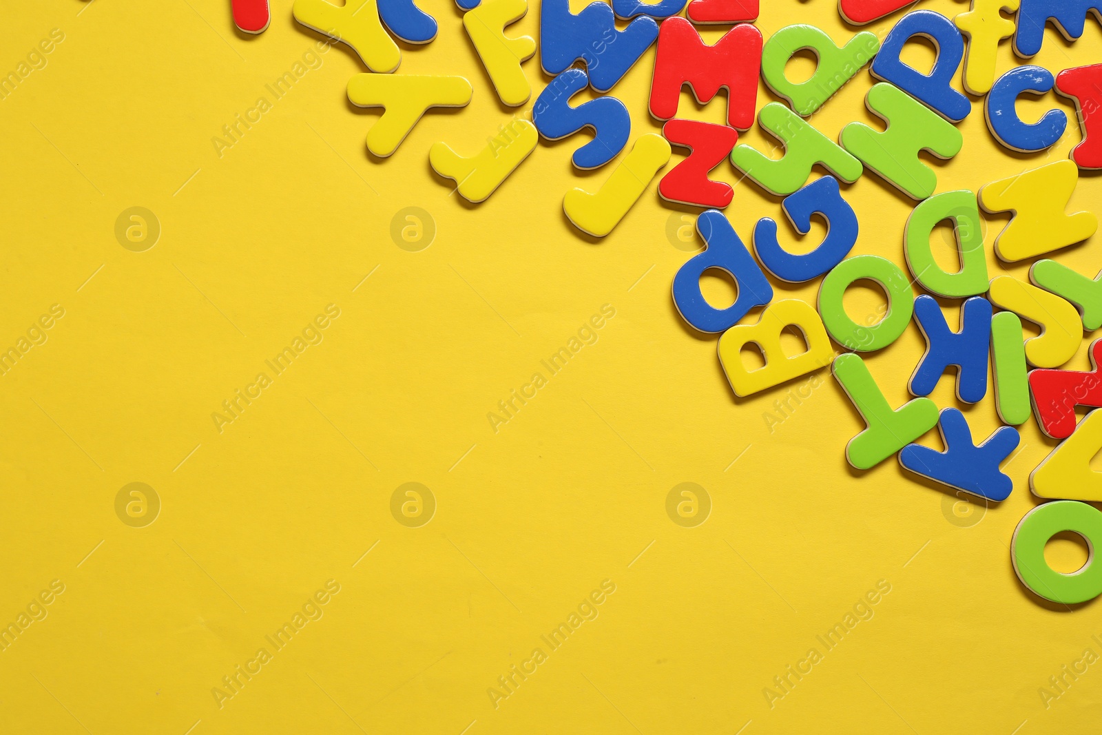 Photo of Learning alphabet. Magnetic letters on yellow background, flat lay. Space for text