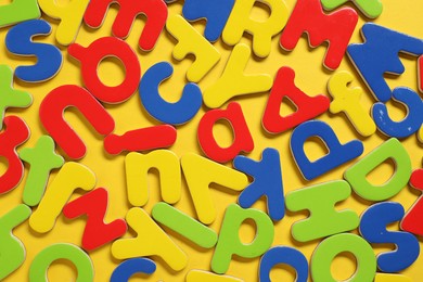 Learning alphabet. Magnetic letters on yellow background, flat lay