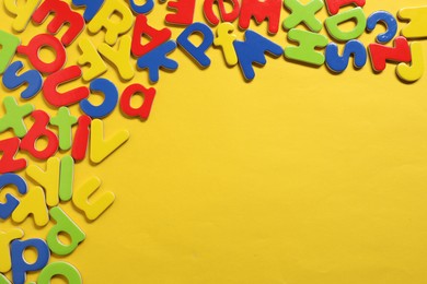 Learning alphabet. Magnetic letters on yellow background, flat lay. Space for text