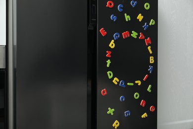 Photo of Many bright magnetic letters on fridge indoors. Learning alphabet