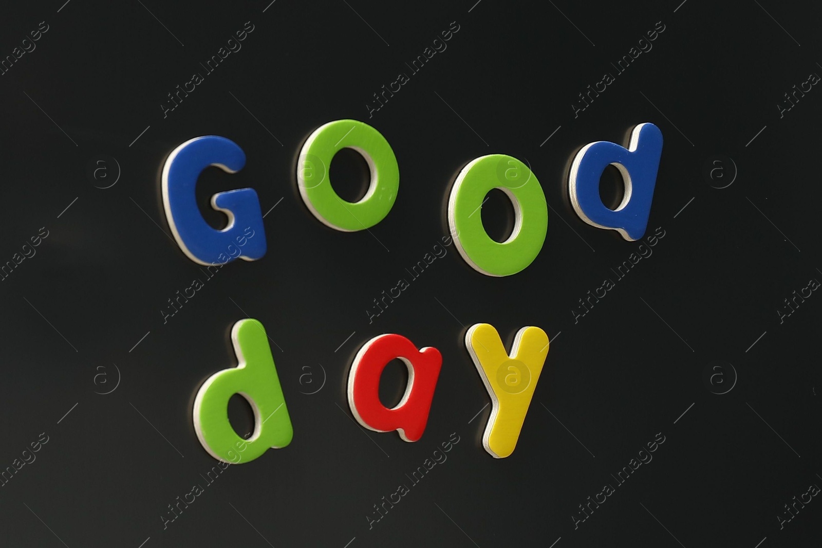 Photo of Phrase Good Day made of bright magnetic letters on fridge. Learning alphabet