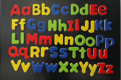 Photo of Alphabetical order. Many bright magnetic letters on fridge