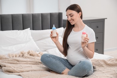 Photo of Expecting twins. Pregnant woman holding two bottles with milk at home, space for text