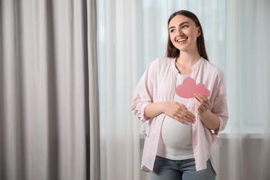 Photo of Expecting twins. Pregnant woman holding two paper cutouts of hearts at home, space for text
