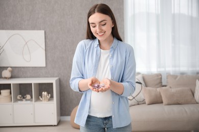 Photo of Expecting twins. Pregnant woman holding two pacifiers at home
