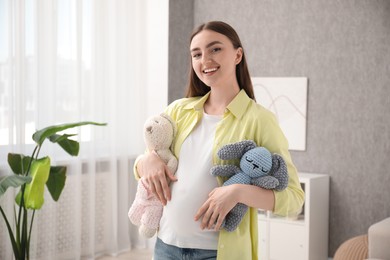 Photo of Expecting twins. Pregnant woman holding two toys at home