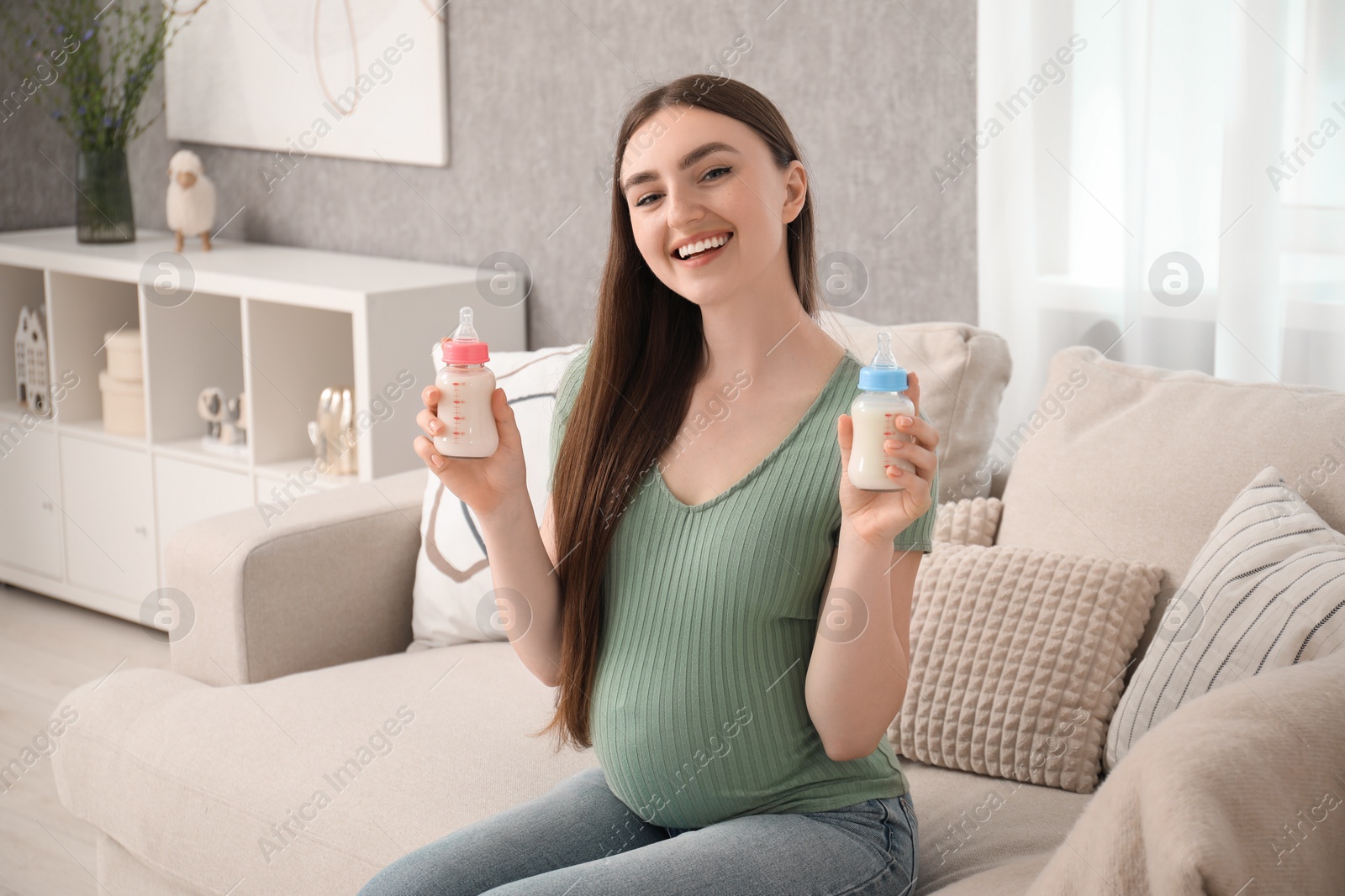 Photo of Expecting twins. Pregnant woman holding two bottles of milk at home