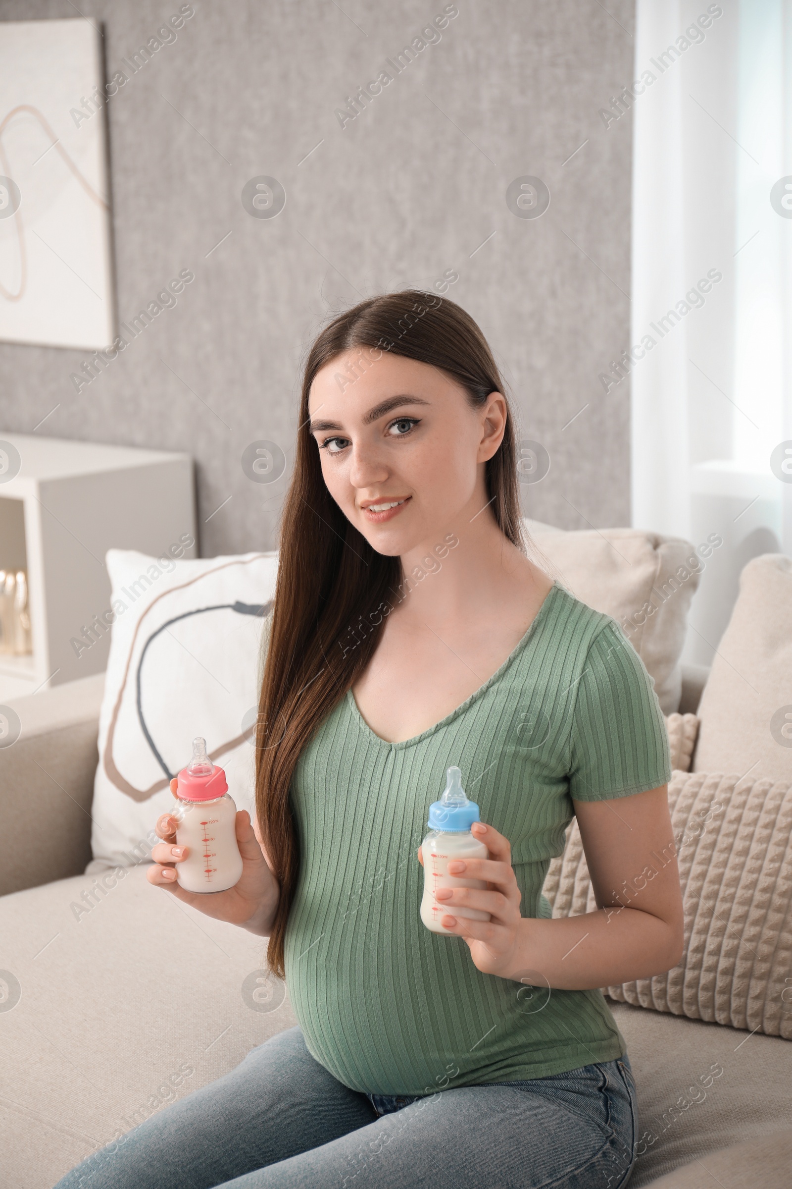 Photo of Expecting twins. Pregnant woman holding two bottles of milk at home