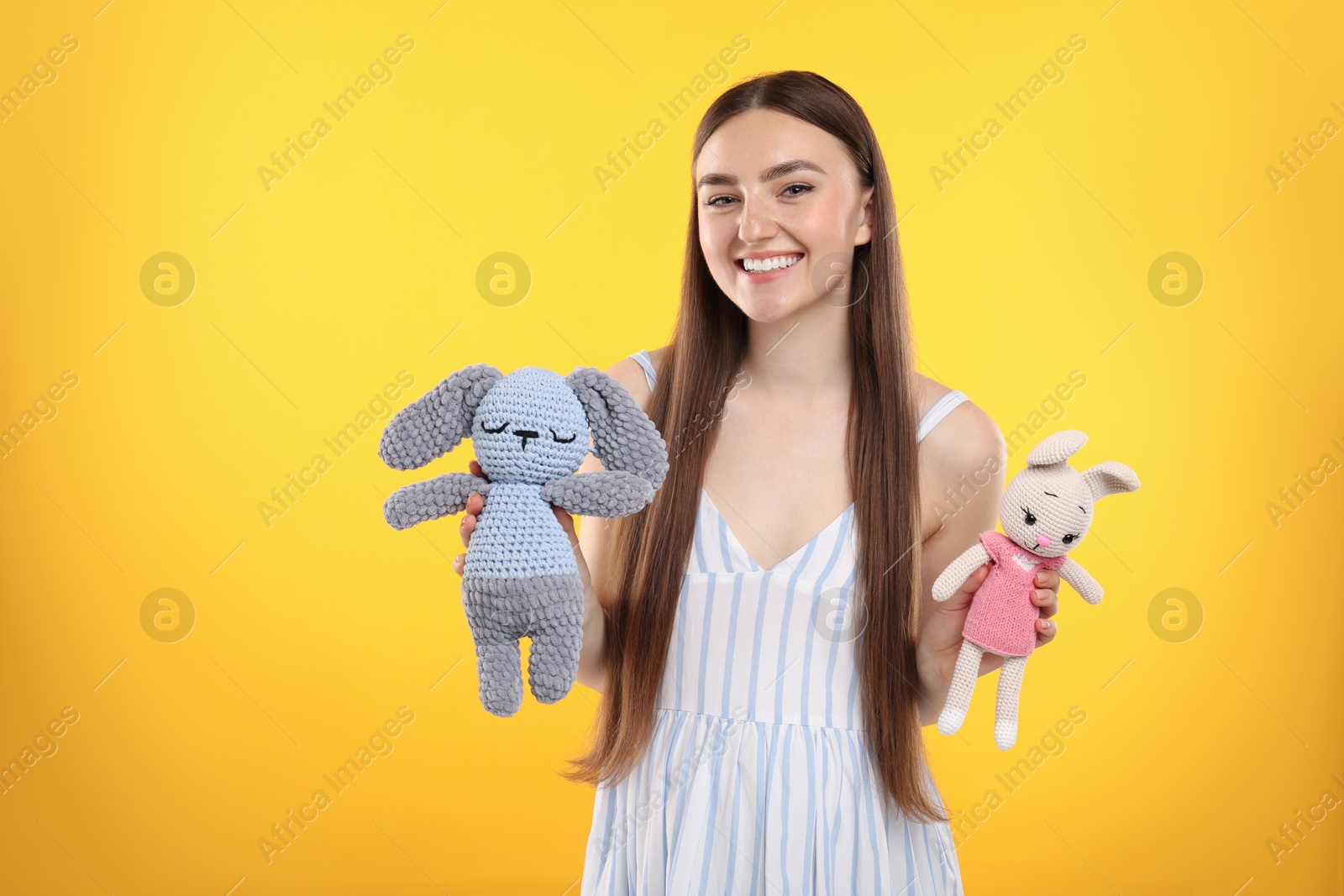 Photo of Expecting twins. Pregnant woman holding two toys on yellow background