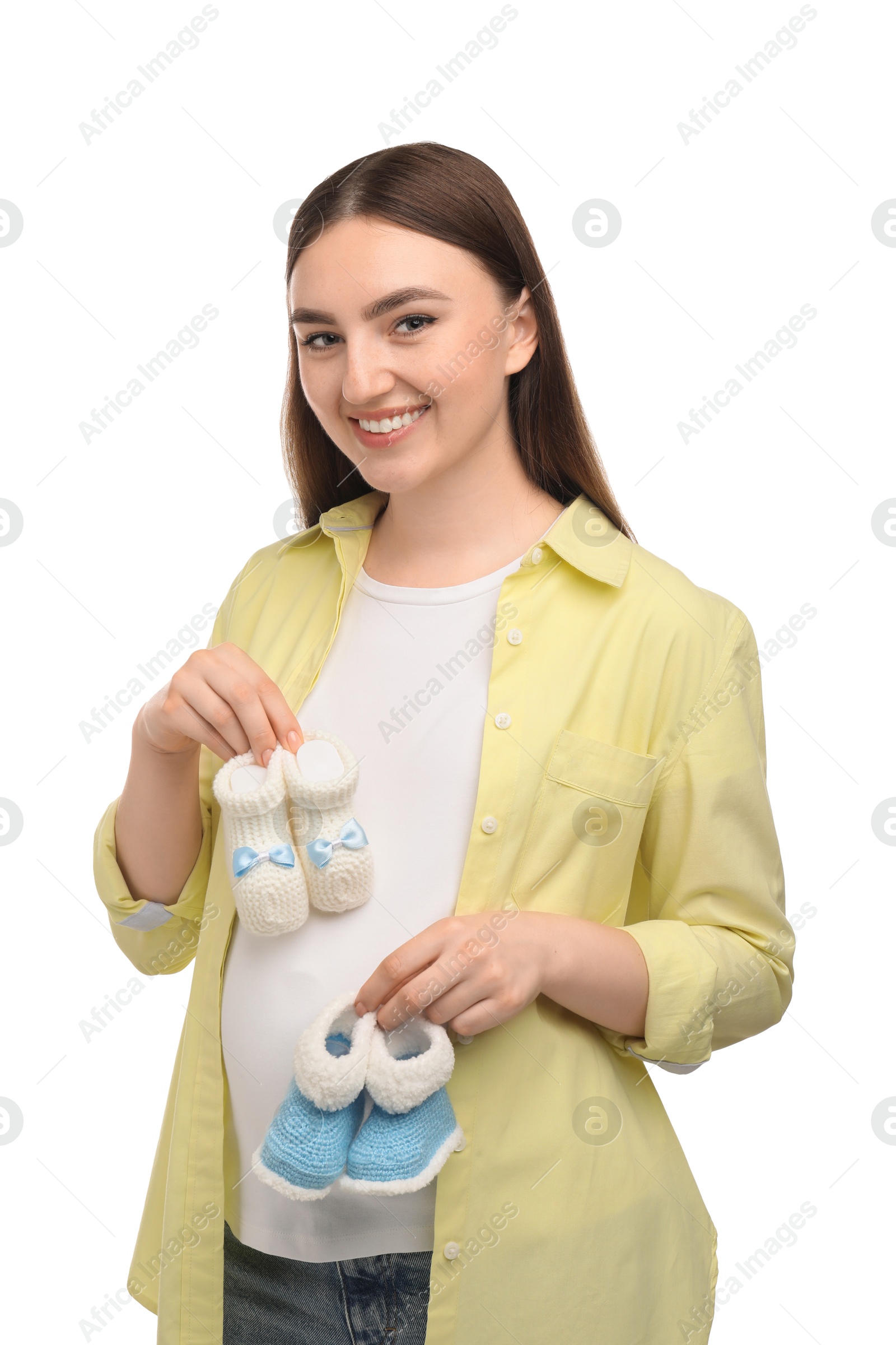 Photo of Expecting twins. Pregnant woman holding two pairs of baby shoes on white background