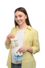 Photo of Expecting twins. Pregnant woman holding two pairs of baby shoes on white background