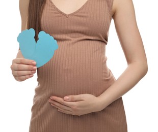 Expecting twins. Pregnant woman holding two paper cutouts of feet on white background, closeup