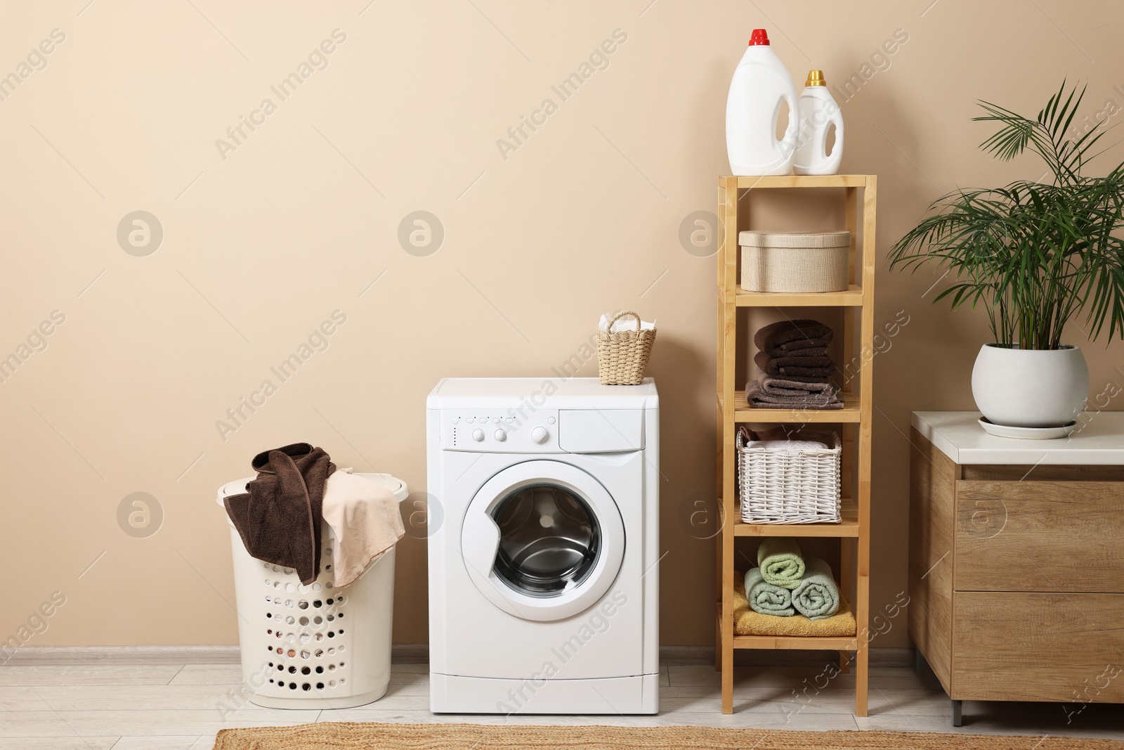 Photo of Stylish laundry room interior with washing machine, furniture and houseplant